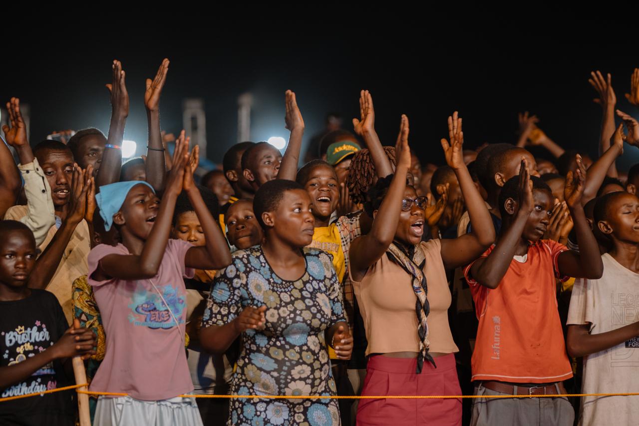 Young people in a Burundi crusade crowd with their hands raised in worship